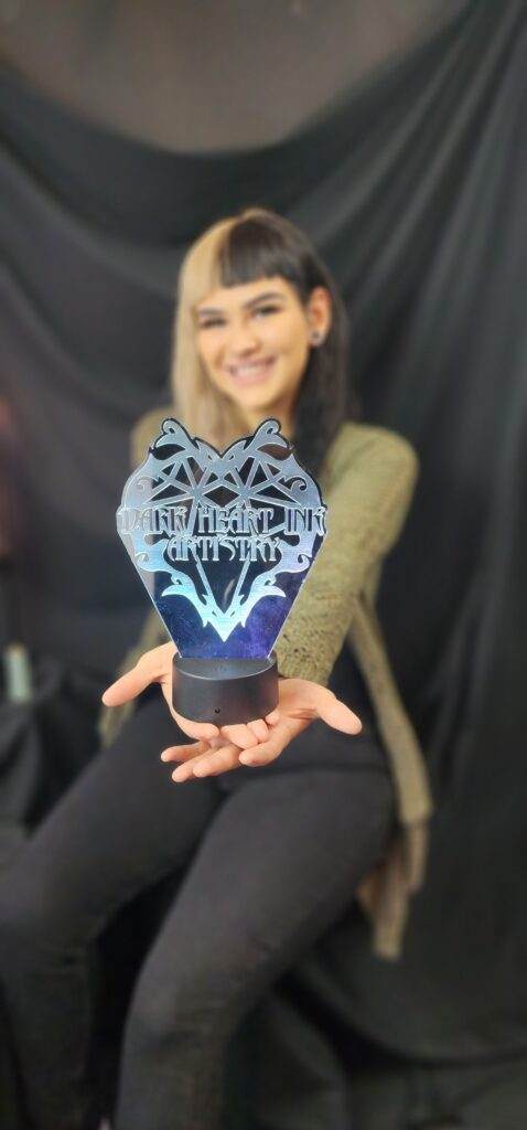 About: A woman is holding up a heart shaped light up sculpture.
