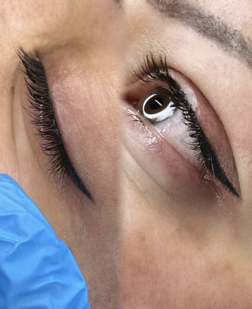 A woman's eye treated with eyelash extensions displayed in a gallery.