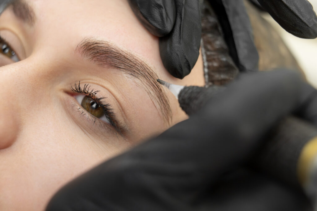 A woman getting her eyebrows tattooed in a salon gallery.