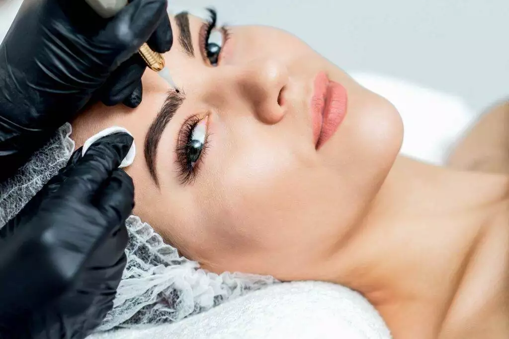 A woman receiving permanent eyebrow makeup in a beauty salon.