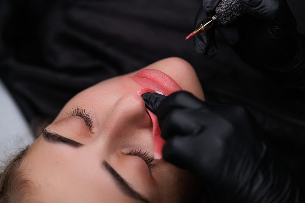 A woman is getting a lip tattoo.