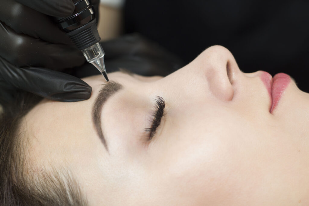 A woman getting her eyebrows tattooed at a beauty salon.